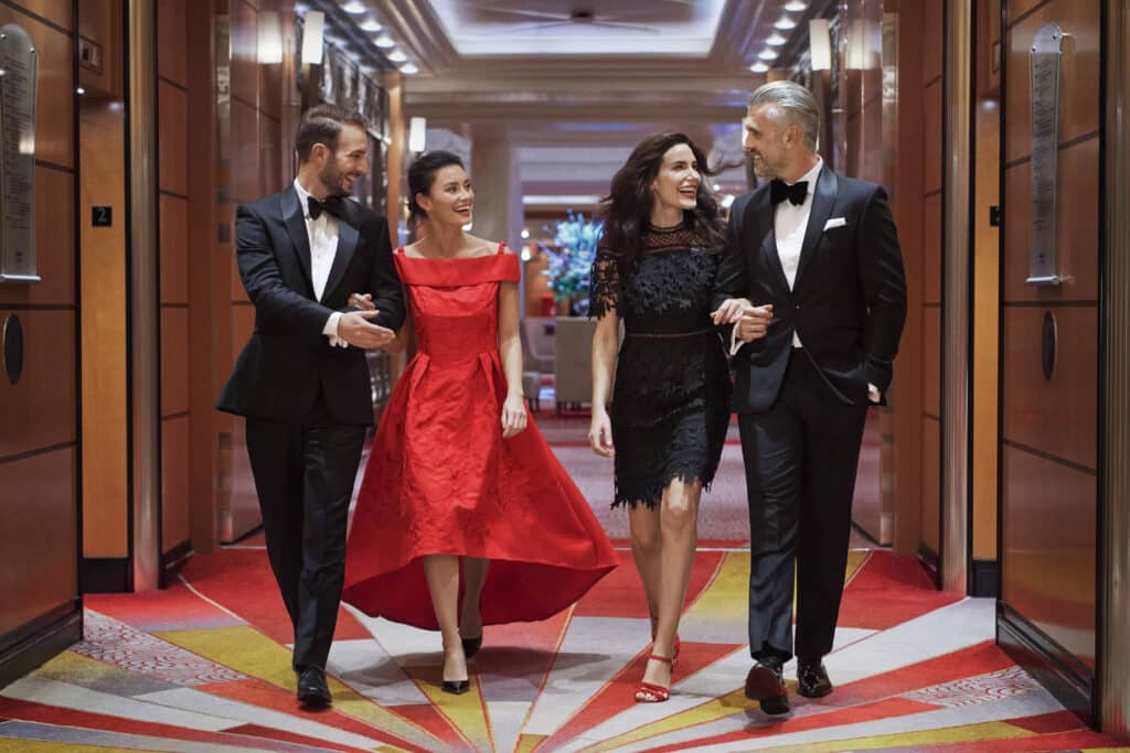 Two couples wearing tuxedos and evening dresses for a gala evening on a cruise ship