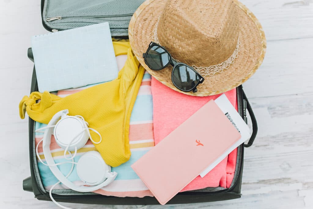 An open suitcase packed with accessories and clothing for a cruise holiday