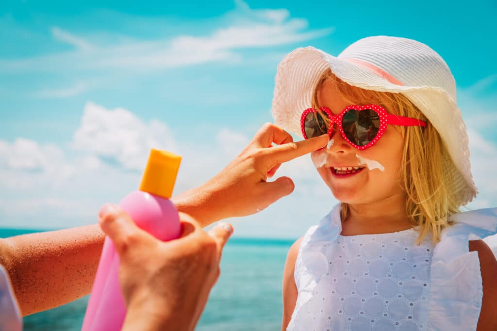 A mum applying sunscreen on her daughter's face - a must-have to pack for any cruise.